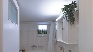 A bathroom with a bathtub, a sink, and a toilet. There is a window with a view of trees, and a plant on the wall. - Neasefessou25 (Kaisariani)