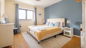 Een slaapkamer met een bed, nachtkastjes, een raam en een lamp.