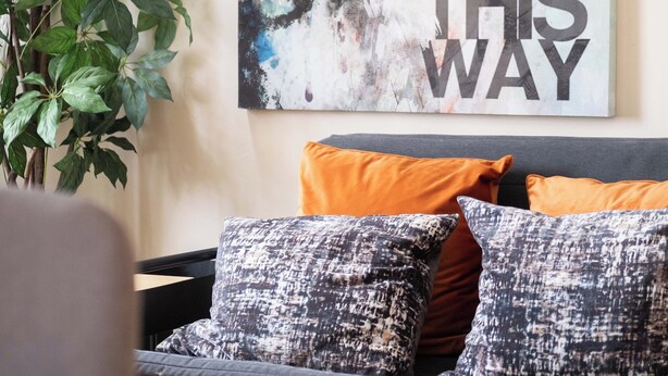 Een slaapkamer met een bed, een groot poster aan de muur en een potplant.