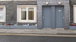 Un bâtiment à deux étages avec une porte grise et un petit porche.