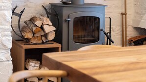 Un interno rustico con un camino in pietra, un tavolo di legno e sedie.