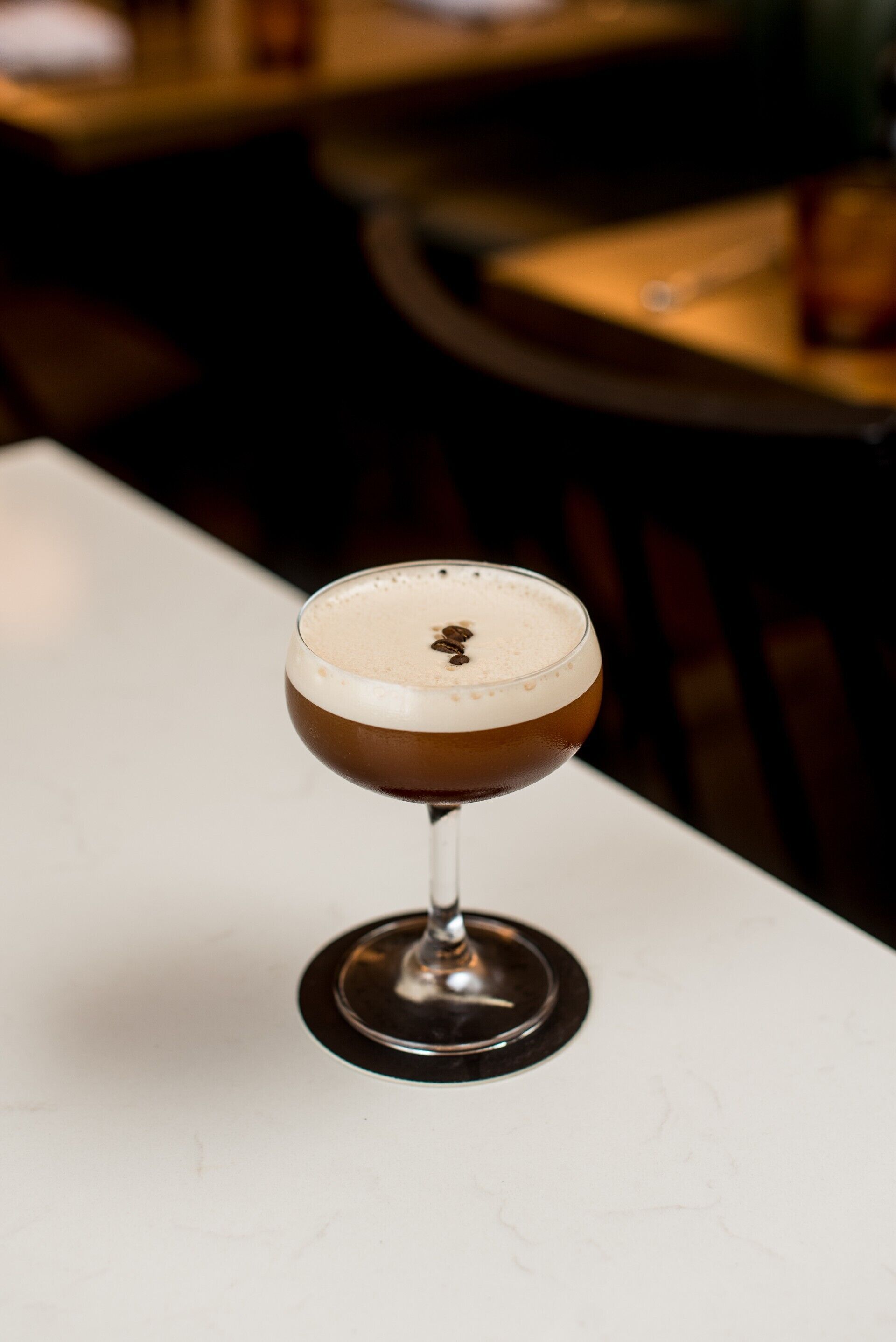 Un cocktail servi dans un verre à pied, posé sur une table blanche.
