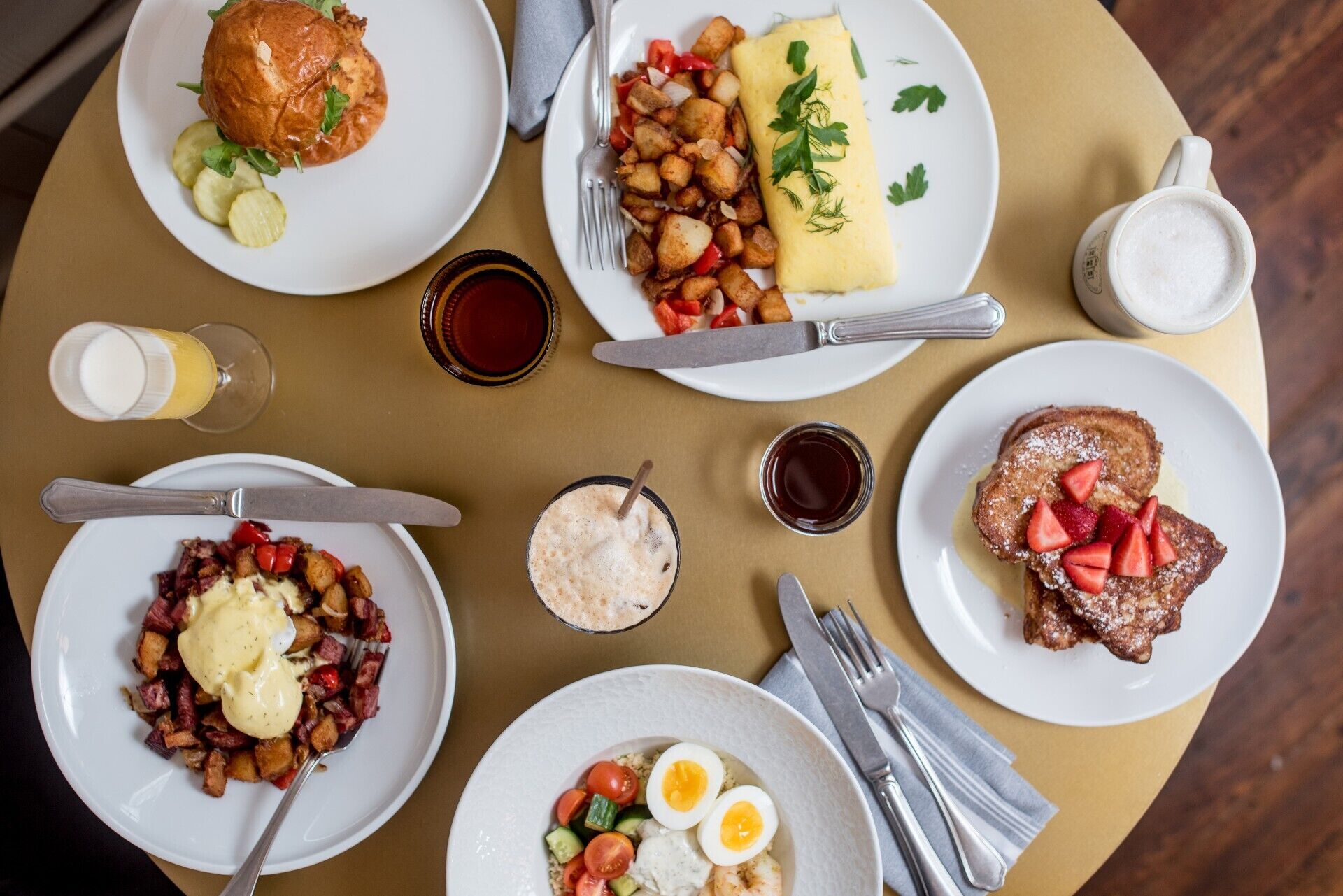A table with various breakfast dishes including eggs, bacon, toast, and a beverage.