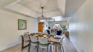 Un coin repas avec une table en bois dressée pour six personnes, entourée de six chaises.