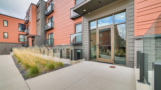 A modern building with a glass entrance, outdoor seating area, and a fire pit. - Walk Everywhere! Central Traverse City Condo (Traverse City)