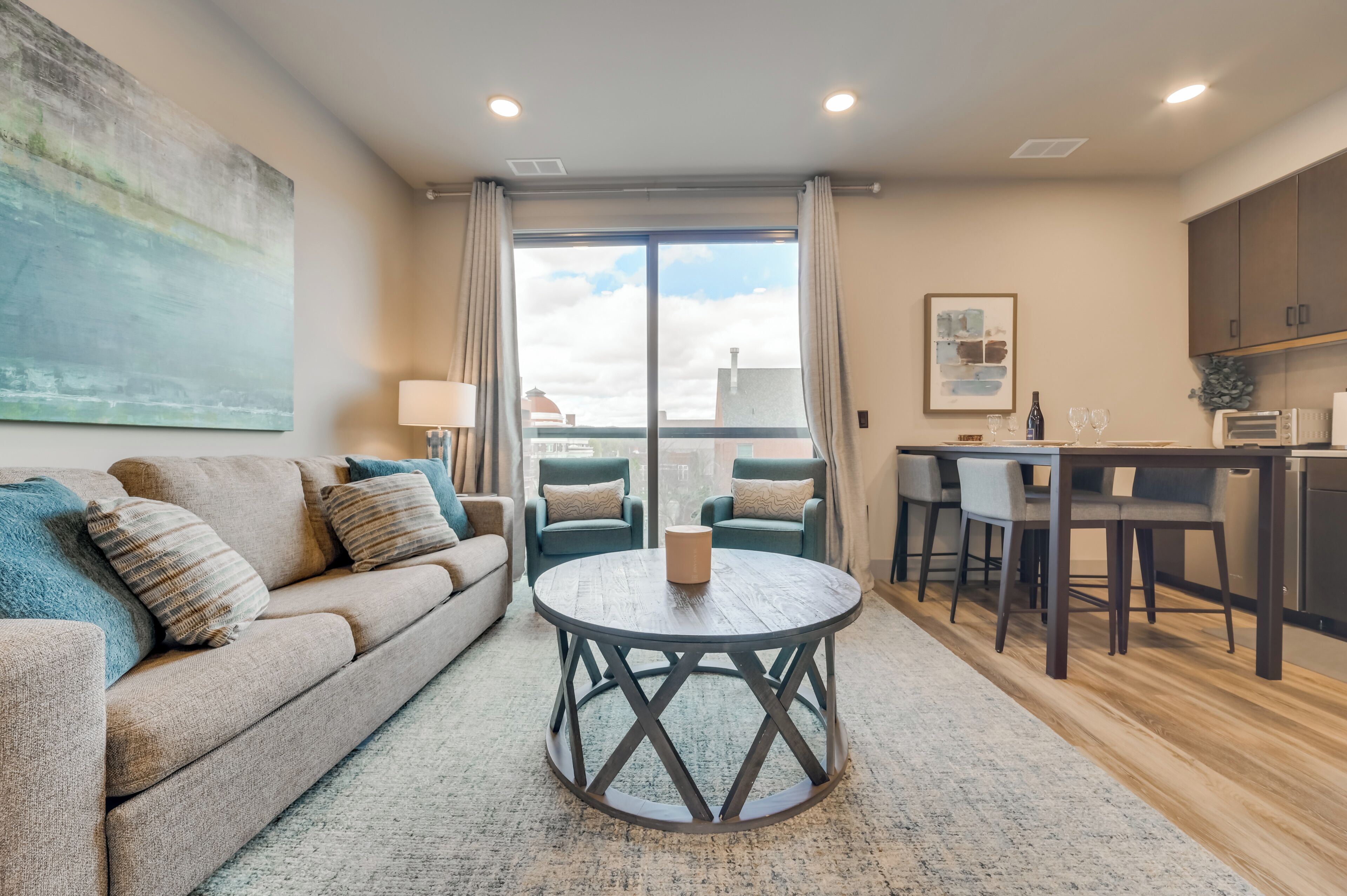 A modern living room with a sofa, a round coffee table, and a dining area with chairs and a table.