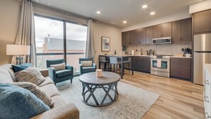 A modern living room with a sofa, chairs, a coffee table, and a view of the outside. - Walk Everywhere! Central Traverse City Condo (Traverse City)