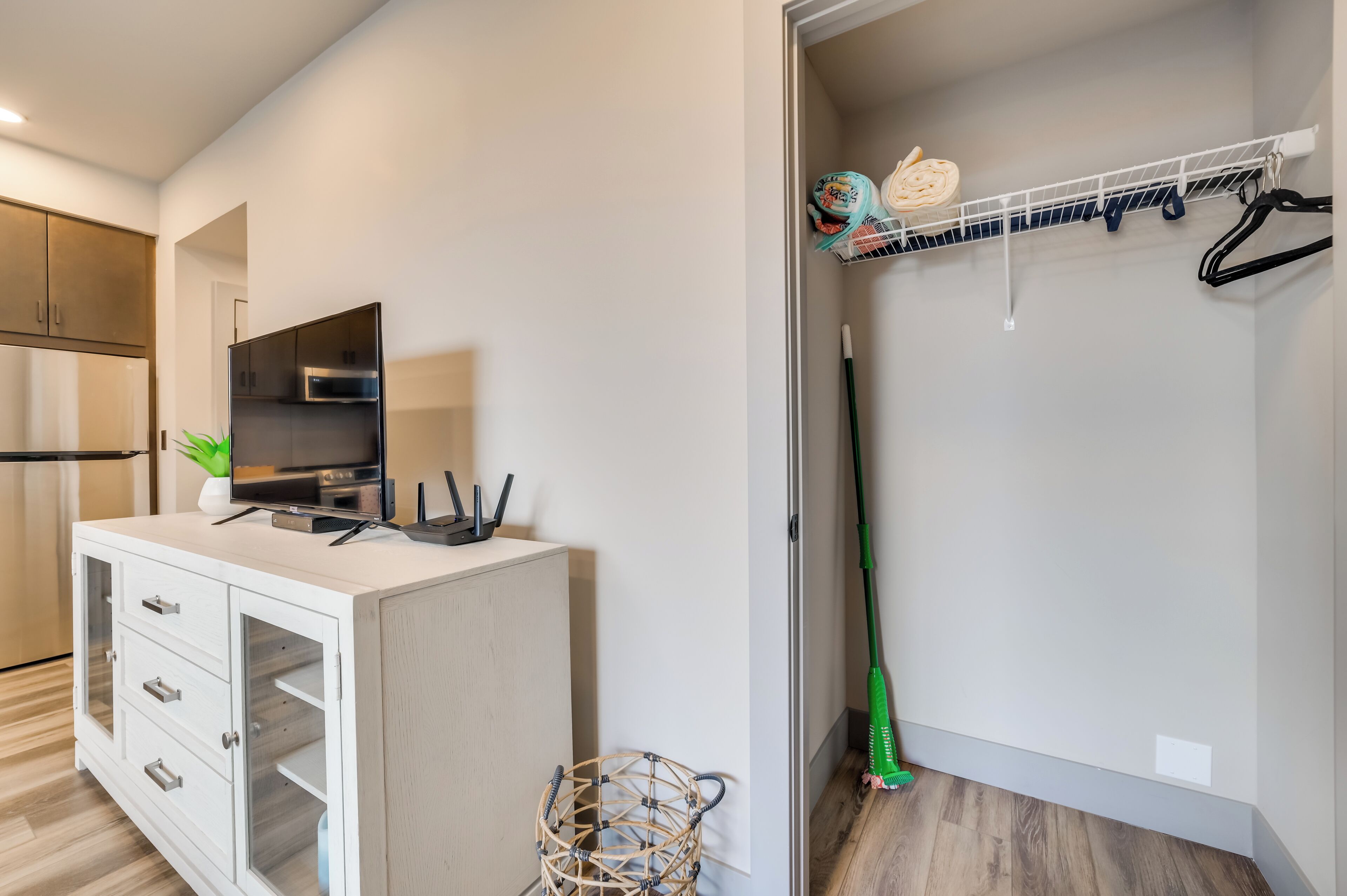 A modern kitchen with a white cabinet, a built-in oven, and a countertop with a television and charging cables.