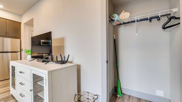 A modern kitchen with a white cabinet, a built-in oven, and a countertop with a television and charging cables.