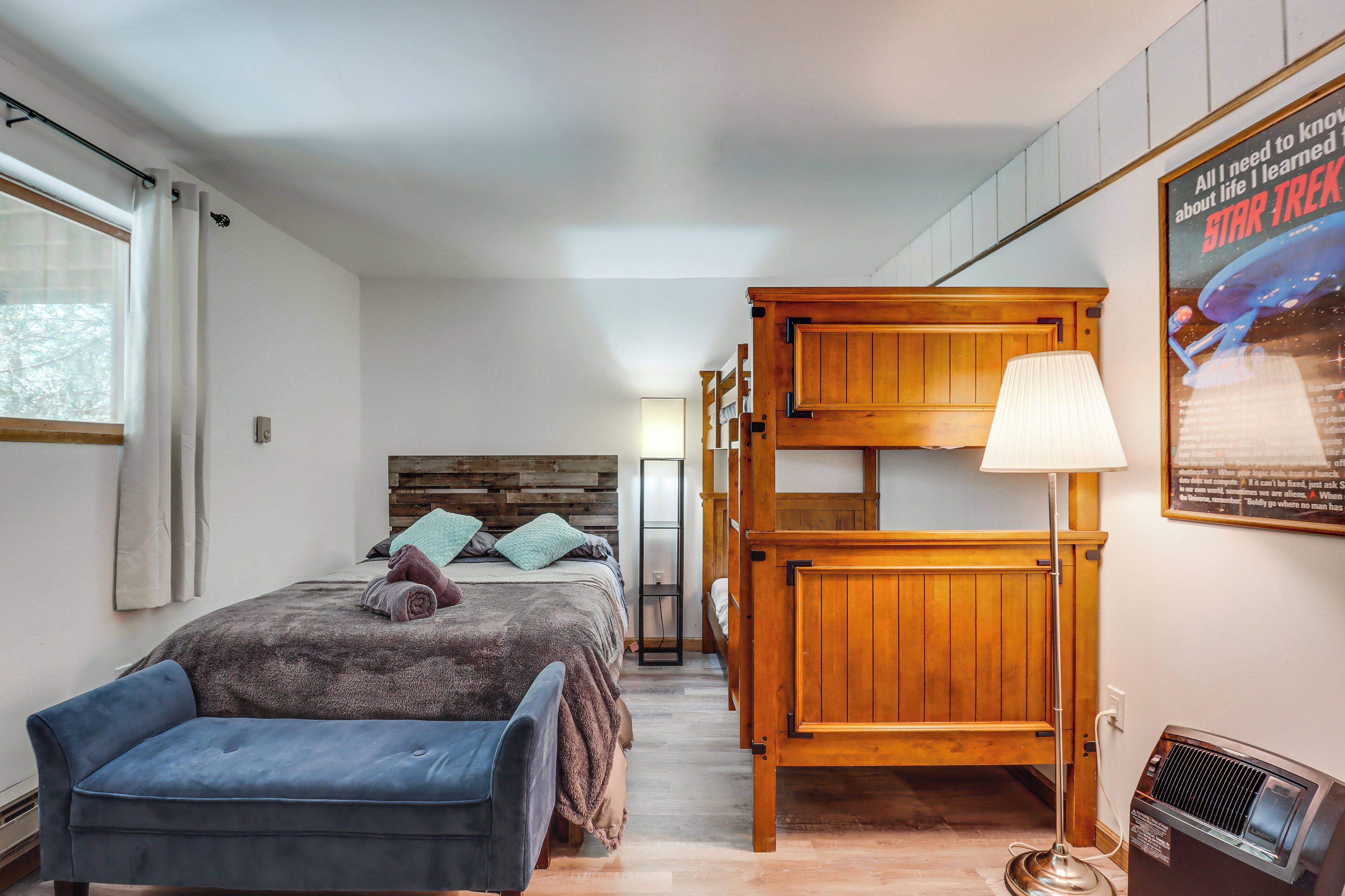 A bedroom with a bunk bed, a bedside table, a lamp, and a poster on the wall.