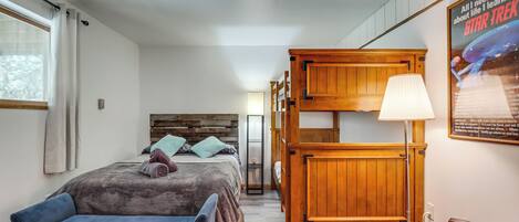 A bedroom with a bunk bed, a bedside table, a lamp, and a poster on the wall.