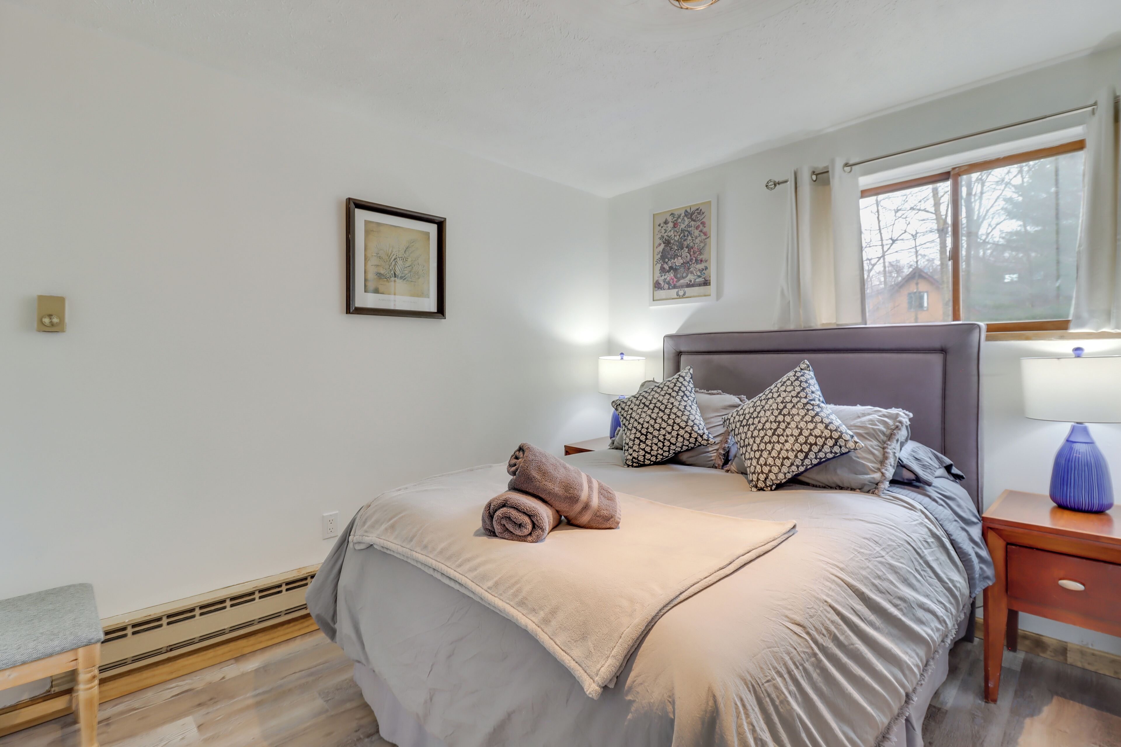 Ein ordentlich eingerichtetes Schlafzimmer mit einem Bett, Nachttischen und einem Fenster.