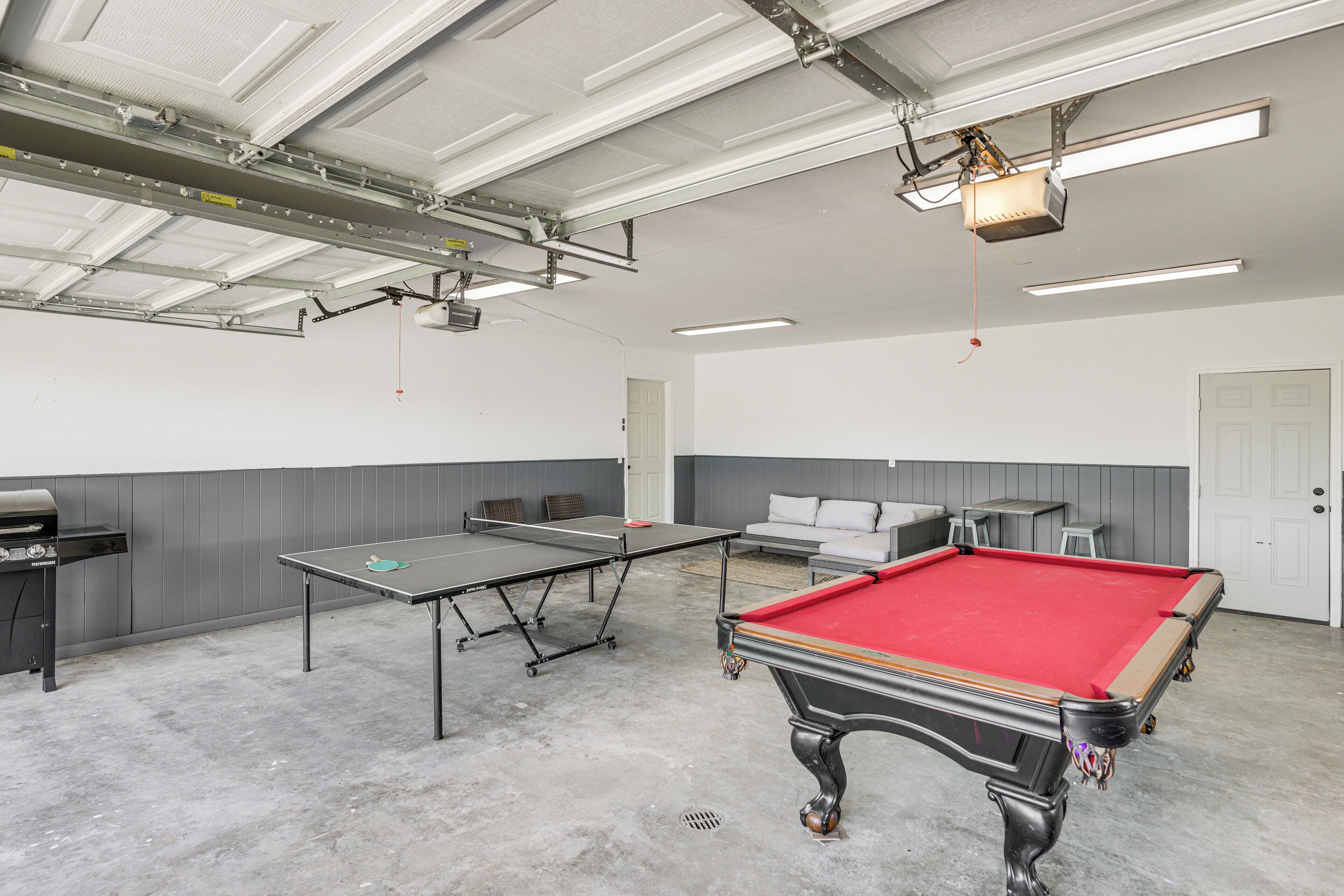 A spacious indoor recreational area with a pool table, ping pong table, and a barbecue grill.