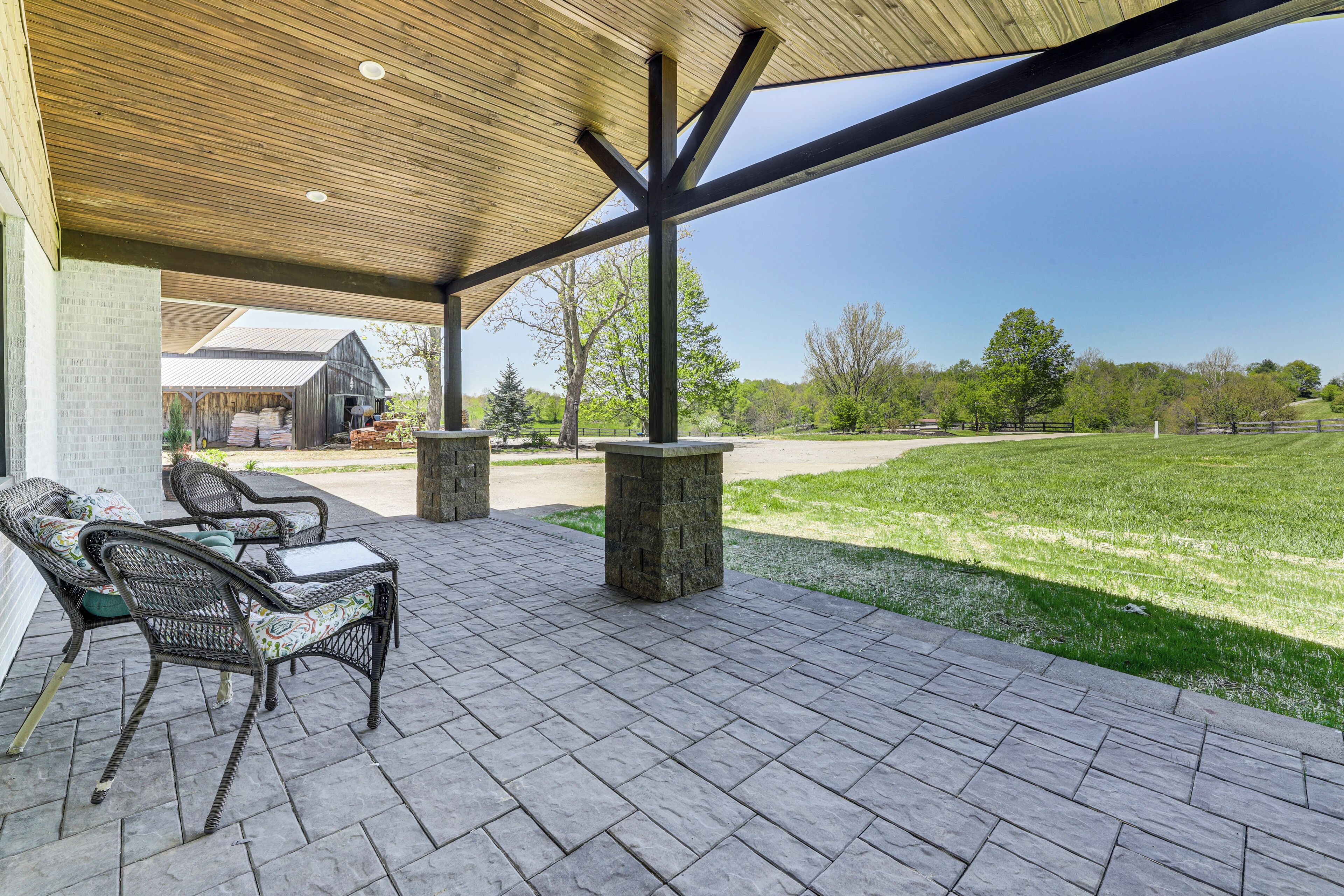 A covered patio area with outdoor furniture and a view of a grassy field.
