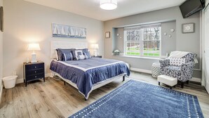 A bedroom with a bed, bedside tables, a chair, a window, and a view of the outdoors. - Indiana Dunes Home w/ Gas Grill: 1 Mi to Beach! (Michigan City)