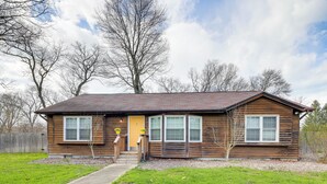 A two-story wooden house with a front porch, a yellow door, and a small front yard. - Indiana Dunes Home w/ Gas Grill: 1 Mi to Beach! (Michigan City)