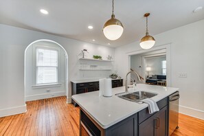 A modern kitchen with a large island, white cabinetry, and a wooden floor. - Elizabeth City Home w/ Fire Pit < 1 Mi to Downtown (Elizabeth City)
