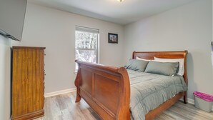 Un dormitorio con cama de madera, una mesita de noche, un armario y una ventana.
