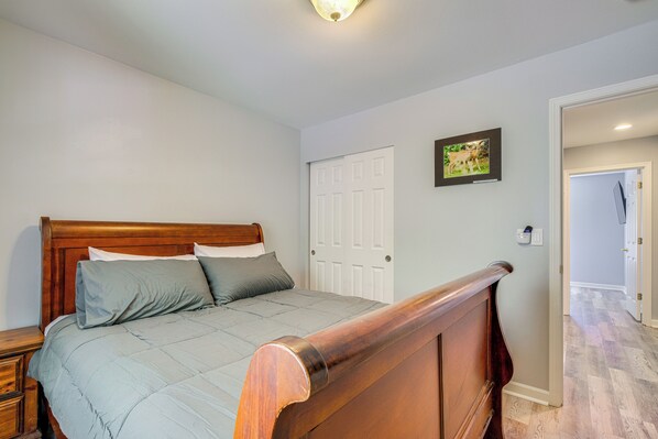 Un dormitorio con una cama de madera, una puerta blanca y un cuadro enmarcado en la pared.