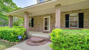 A two-story brick house with a covered porch and a front door. - Perry Family Home on 2 Acres w/ Private Pool (Perry)
