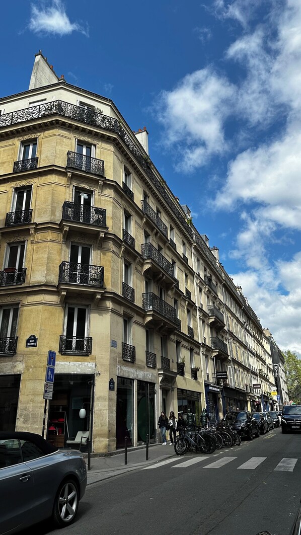 A multi-story building with balconies, a visible entrance, and a sign indicating a hotel.