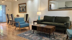 Ein Wohnzimmer mit Sofa, Sessel, Couchtisch und Teppich.