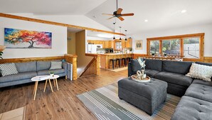 A spacious living area with a sofa, ottoman, and a dining area with a bar. - The Treehouse @ Higgins Lake-HOT TUB- Fireplace-Pets❤️-3 min walk to the lake (Roscommon)