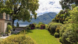 A lush garden with a lawn, benches, and a view of mountains and a lake. - Villa Artemisia by MyVillaCollection (Lenno)