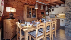 A wooden cabin-style kitchen with a dining table set for four, wooden chairs, and pendant lights. - Meribel Les Allues Ski Chalet With Beautiful Views Of The Mountains (Les Allues)