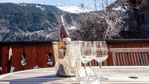 A table with a wine bottle and glasses, set against a mountainous backdrop. - Meribel Les Allues Ski Chalet With Beautiful Views Of The Mountains (Les Allues)