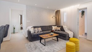 A modern living room with a grey sectional sofa, a wooden coffee table, and yellow ottomans. - Luxury Apartment Silvery Split with Sauna, Jacuzzi (Split)
