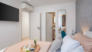 A modern hotel room with a bed, a TV mounted on the wall, and a breakfast tray on the bed. - Luxury Apartment Silvery Split with Sauna, Jacuzzi (Split)