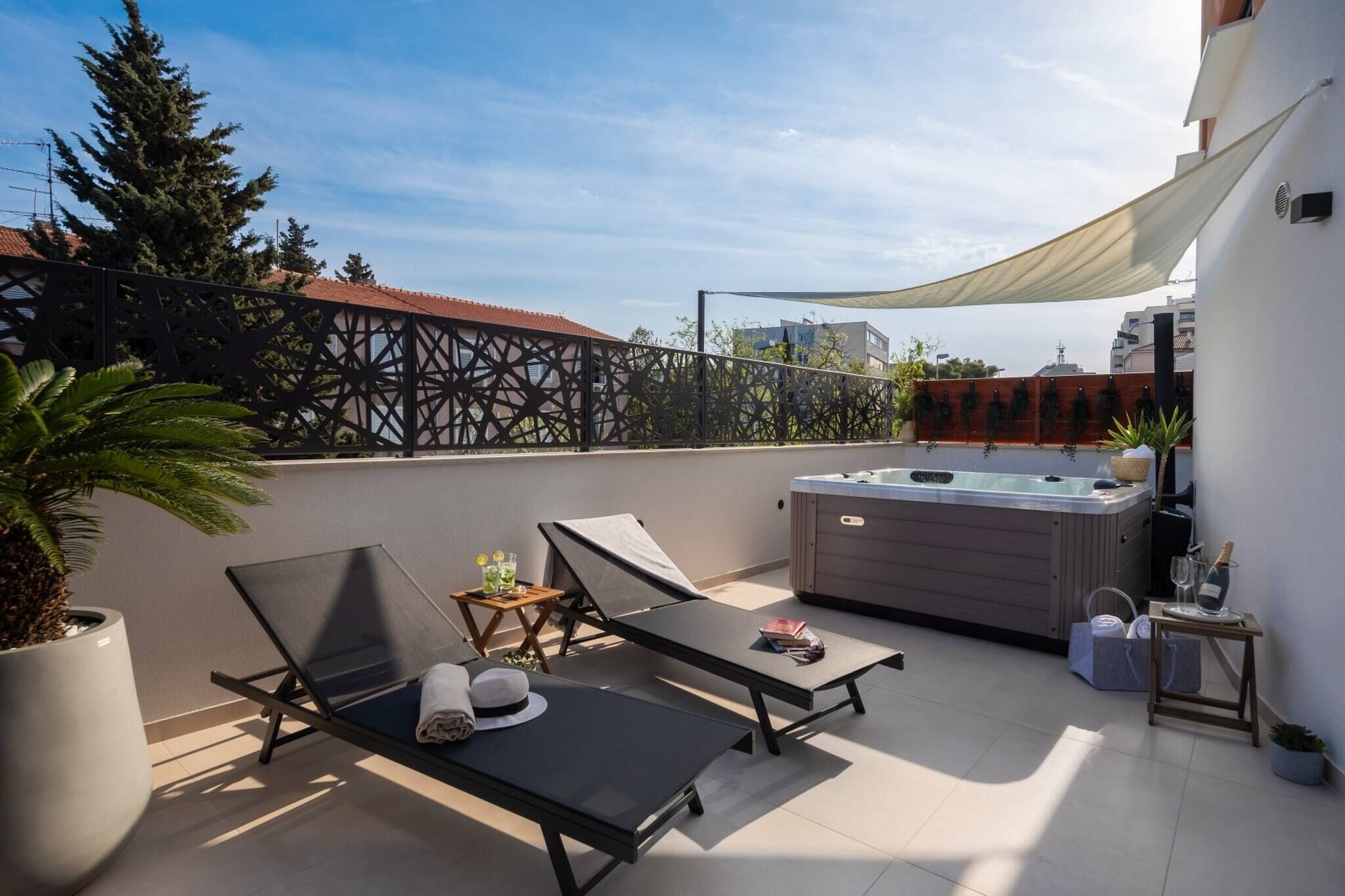 Una terrazza sul tetto con due poltrone da relax, una vasca idromassaggio e una pianta in vaso.