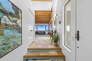 A hallway with a stone floor leading to a living area with a view.