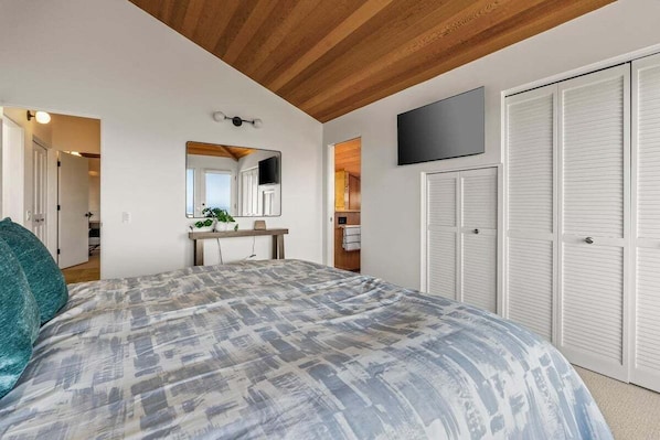 Quarto com cama, espelho, televisão e guarda-roupa.