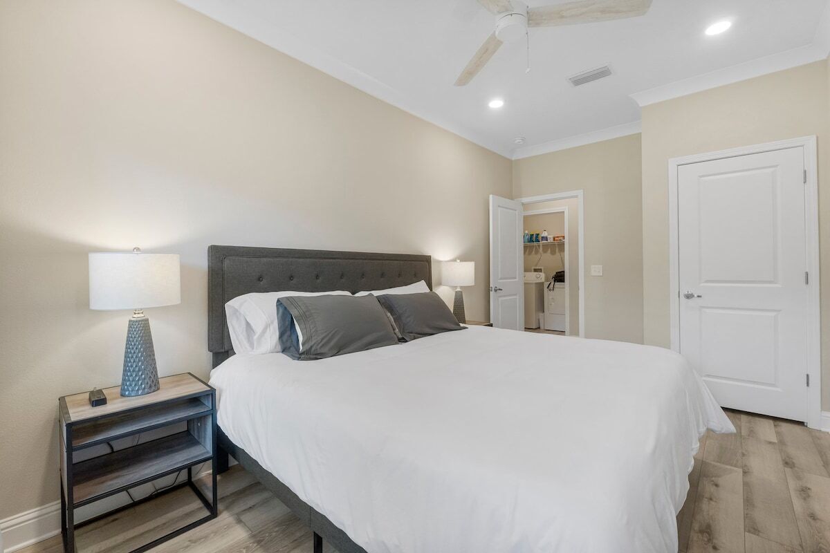 A bedroom with a bed, nightstands, a ceiling fan, and a door.