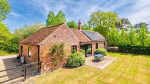 A brick house with a sloped roof, a solar panel, and a patio with a table and chairs. - Harnser Barn, Tittleshall, Norfolk (Tittleshall)