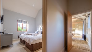 A bedroom with a large bed, a bedside table, and a window with curtains. - Harnser Barn, Tittleshall, Norfolk (Tittleshall)
