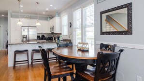 Una cocina moderna con armarios blancos, una isla central e iluminación colgante.