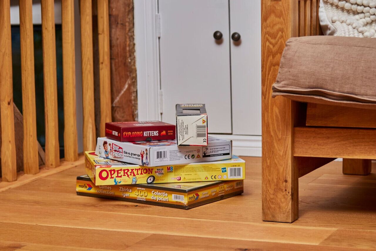A stack of books on a wooden floor near a door and a bench.