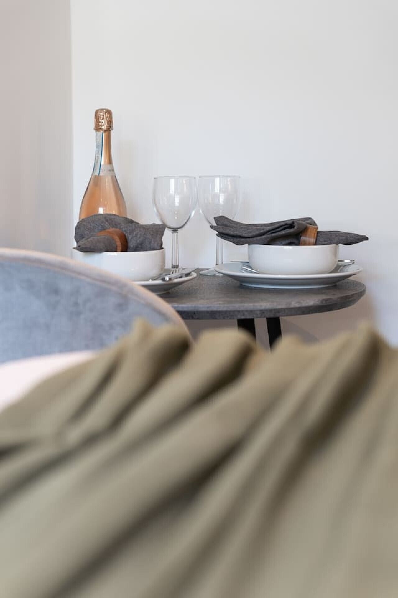 Une table à manger avec une bouteille, deux verres et une serviette en tissu.
