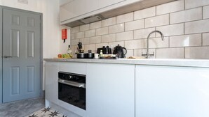 A modern kitchen with white cabinets, a stainless steel oven, a sink, and a tiled backsplash. - Sleek City Stay; Long Stay Discount, FREE Parking (Southampton)