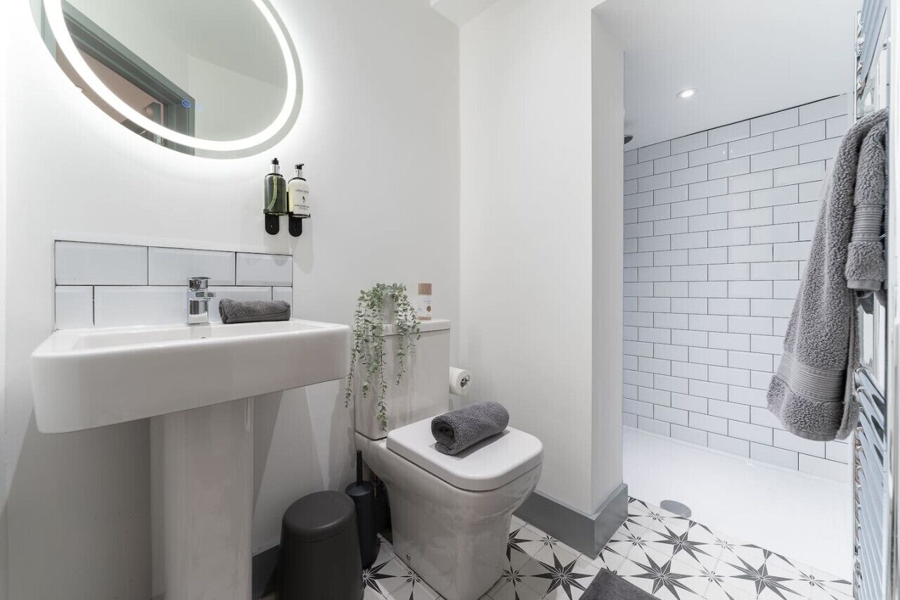 A modern bathroom with a white sink, a toilet, and a shower area.