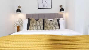 A neatly made bed with patterned pillows, a headboard, and two wall-mounted lamps. - Bright Courtyard Apt • Free Laundry & Parking (Southampton)