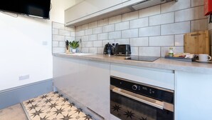 A modern kitchen with white tiles, a built-in oven, and a coffee maker on the counter. - Stylish Studio; Free Laundry, Long Stay Discounts (Southampton)