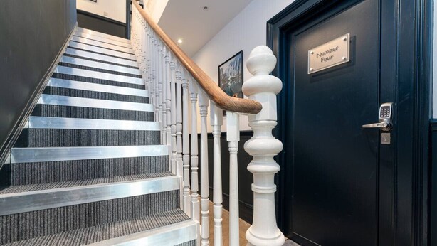 A staircase with a modern design, featuring a metal handrail and carpeted steps. - Roomy Studio Apt • Fast Wi-Fi, Parking & Laundry (Southampton)