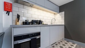 A modern kitchen with white cabinets, a black oven, and a tiled backsplash. - Roomy Studio Apt • Fast Wi-Fi, Parking & Laundry (Southampton)