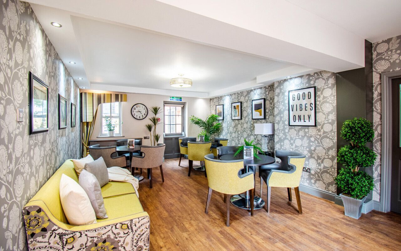 A modern hotel lobby with a sofa, dining area, and decorative plants.