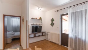 Un espacio habitable compacto con cama, televisor, mesa de comedor y radiador.