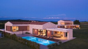 Une maison moderne dotée d’une piscine, de grandes fenêtres et d’une pelouse bien entretenue.